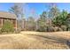 View of the backyard with mature trees, landscaped shrubbery, and dormant lawn at 103 Old Avery Dr, Canton, GA 30115