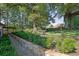 Private backyard featuring a stone retaining wall, lush landscaping, and mature trees at 2295 Hemrick Rd, Cumming, GA 30041