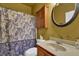 This bathroom has a floral shower curtain, cabinet, sink, and round mirror at 2295 Hemrick Rd, Cumming, GA 30041