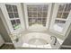 Bright bathroom features a soaking tub with jets set beneath a bay window with a wooded view at 9470 Dominion Way, Alpharetta, GA 30022