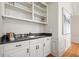 Charming wet bar featuring custom white cabinets, dark granite counters, and open display shelving for glassware storage at 9470 Dominion Way, Alpharetta, GA 30022