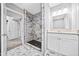Bathroom with a white vanity cabinet, granite countertop, framed mirror and a shower with marble-patterned tile at 2814 Lloyd Rd, Decatur, GA 30034
