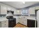 Kitchen with white cabinets, black appliances, and wood-look flooring at 1057 Forest Path, Stone Mountain, GA 30088