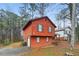 Side view of red two-story home showing attached garage, dark shutters, and a tree-filled lot at 1057 Forest Path, Stone Mountain, GA 30088