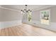 Bright living room featuring modern light fixture, two windows, beautiful wood floors, and decorative wall trim at 743 Cedar Sw Trce, Lilburn, GA 30047
