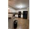Well-lit kitchen with white cabinets, black appliances, and neutral tile flooring at 7248 Mountain Laurel Way, Stockbridge, GA 30281