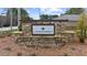 Attractive stone entrance sign for Lakecrest community, with well-maintained landscaping and colorful flowerbeds at 6451 Crest Brook Way, Buford, GA 30518