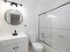 Modern bathroom with a sleek vanity, round mirror, and a glass-enclosed shower/tub at 742 Olde Towne Ln, Marietta, GA 30068