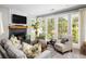 Elegant living room featuring a fireplace, large windows and comfortable seating bathed in natural light at 10594 Serenbe Ln, Chattahoochee Hills, GA 30268