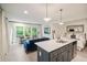 Open living space with a modern kitchen island, seating area, and bed with white linens at 10594 Serenbe Ln, Chattahoochee Hills, GA 30268