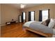 Bright main bedroom with a king-size bed, hardwood floors, three windows, and dark colored curtains at 132 Wetherbrooke Ln # 3, Smyrna, GA 30082