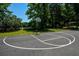 Outdoor basketball court featuring white line paint, lush grass and green trees at 100 Silverbell Ct, Roswell, GA 30075