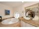 Relaxing bathroom showcasing an oval bathtub, granite countertop, and decorative mirrors at 100 Silverbell Ct, Roswell, GA 30075