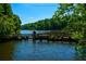 Picturesque lake view featuring a wooden bridge amidst a backdrop of lush green trees at 100 Silverbell Ct, Roswell, GA 30075