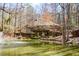 Scenic view of pond with fountain and charming home with wraparound deck in wooded setting at 100 Silverbell Ct, Roswell, GA 30075