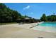 Community pool featuring an open-air pavilion, tables, and accessible entry with lush green trees in the background at 100 Silverbell Ct, Roswell, GA 30075