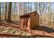 Charming shed in a wooded area with a small window and decorative sunburst above the door at 100 Silverbell Ct, Roswell, GA 30075