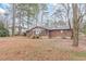 View of a brick home with a large backyard featuring mature trees and a screened-in porch with stairs at 50 Carriage Trce, Stockbridge, GA 30281