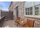 Relaxing balcony with two wooden chairs, small table, and brick exterior of the home at 145 Rose Garden Ln, Alpharetta, GA 30009