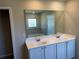 Bathroom vanity featuring double sinks, white cabinets and a large mirror at 738 Basswood Ave, Mcdonough, GA 30252