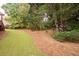 Home backyard featuring lush greenery, mature trees, and a mulch bed at 4651 Oakleigh Manor Dr, Powder Springs, GA 30127