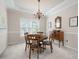 Traditional dining room featuring a round wooden table, classic chandelier, and elegant wainscoting details at 4651 Oakleigh Manor Dr, Powder Springs, GA 30127