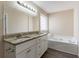 Luxurious bathroom with double sink vanity, soaking tub, granite countertops, and white cabinets at 6557 Snow Bird Ln, Douglasville, GA 30134