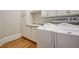 Well-lit laundry room with white cabinetry, modern washer and dryer units, and a 