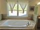 Large soaking tub with neutral tile surround and lots of natural light from the window at 4188 Gunnerson Ln, Kennesaw, GA 30152