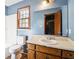 Standard bathroom featuring blue walls, mirror, and a window bringing in natural light at 8673 Collins Dr, Jonesboro, GA 30236