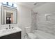 Bathroom featuring a black framed mirror, gray tiled wall, white sink, toilet, and tub at 3637 Eaglerock Dr, Atlanta, GA 30340