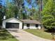 Charming single-story home featuring a dark garage door, well-manicured lawn, and beautiful surrounding trees at 1449 Albans Ct, Lithonia, GA 30058