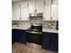 Modern kitchen featuring stainless appliances, granite counters, stylish white backsplash, and blue and white cabinets at 1449 Albans Ct, Lithonia, GA 30058