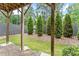 Tranquil backyard featuring a manicured lawn, evergreens, and a cozy covered patio area at 2452 Coosa Vly, Atlanta, GA 30339