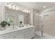 Bright bathroom featuring double sinks, white cabinets, and a glass-enclosed shower at 2452 Coosa Vly, Atlanta, GA 30339