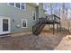 A lush green home with a backyard featuring a stone patio and a dark wood staircase leading to a deck at 1008 Poplar Grv, Woodstock, GA 30189