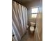 Cozy bathroom featuring a window, tiled floors, and a shower with a striped curtain at 3740 Tupelo Trl, Auburn, GA 30011