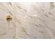 Close-up of the shower with elegant marble tile and gold fixtures at 2691 Jamerson Rd, Marietta, GA 30066