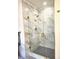 A glass shower with brown and white marbled tile and a black tile floor at 2691 Jamerson Rd, Marietta, GA 30066