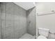 Bathroom shower with gray tiled walls, a shower head, and modern fixtures in a neutral color palette at 3100 Parc Lorraine, Lithonia, GA 30038