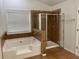 Bathroom featuring a soaking tub and tiled shower with a glass door and window at 868 Still Hill Ln, Lawrenceville, GA 30045