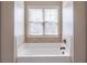 Close up of a bathtub in bathroom with white tile surround and natural light from the window at 965 Mulberry Bay Dr, Dacula, GA 30019