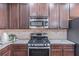 Kitchen features stainless steel oven, microwave, granite counters and backsplash, and dark wood cabinets at 965 Mulberry Bay Dr, Dacula, GA 30019