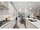 Modern kitchen with white cabinets, stainless steel appliances, and view to the open concept living room and outdoor patio at 642 Stickley Oak Way, Woodstock, GA 30189