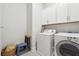 Convenient laundry room features white cabinets and modern washer and dryer at 642 Stickley Oak Way, Woodstock, GA 30189
