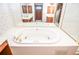 Bathroom featuring a large white soaking tub with gold fixtures and a tiled surround for relaxation at 1975 Skidmore Cir, Lawrenceville, GA 30044