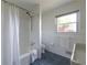 Bright bathroom with white tiled walls, tub shower, toilet, and dark blue tile floor at 412 E Pharr Rd, Decatur, GA 30030