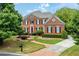 Beautiful brick two-story home with a well-manicured lawn, mature trees, and a circular driveway at 195 High Bluff Ct, Duluth, GA 30097