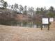 Scenic view of the community pond featuring posted rules and surrounded by mature trees at 1365 Willis Lake Dr, Kennesaw, GA 30152