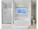 Bright bathroom with a soaking tub, glass-enclosed shower, and tiled floors at 1935 Wenton Pl, Lawrenceville, GA 30044